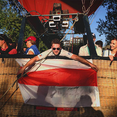 Oro baliono pilotas laikantis vėliavą krepšyje